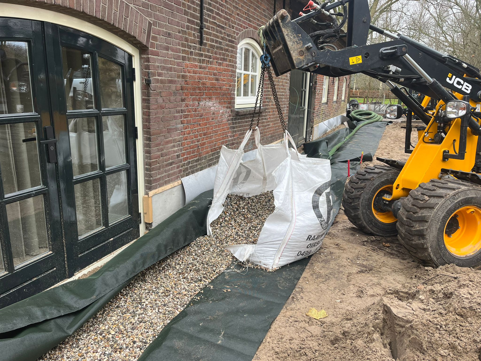 Drainagewerkzaamheden langs een pand met een graafmachine