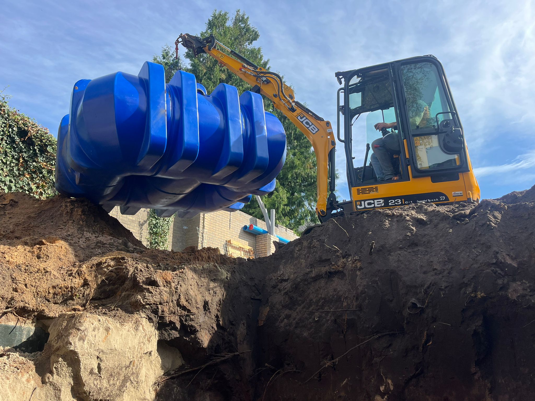 Plaatsing van een blauwe ondergrondse watertank met een graafmachine